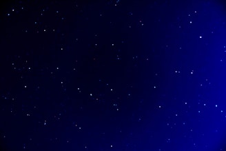 A deep blue night sky scattered with numerous small stars, creating a serene and expansive view of the universe.
