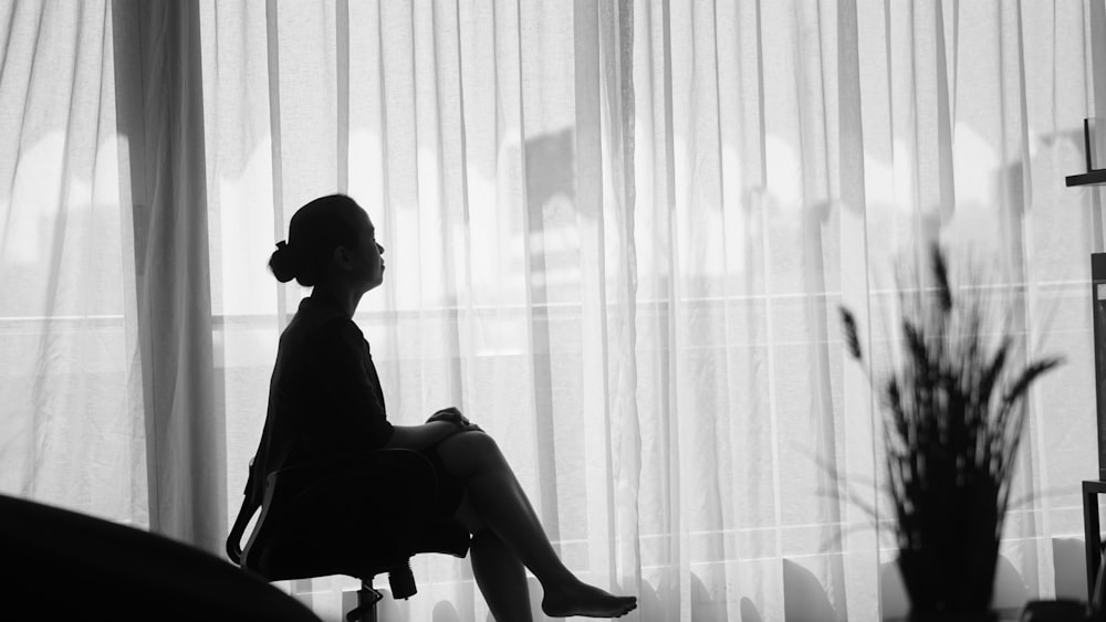 窓際のオフィスのローリングアームチェアに座る女性