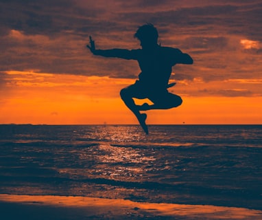 silhouette of man jump on seashore