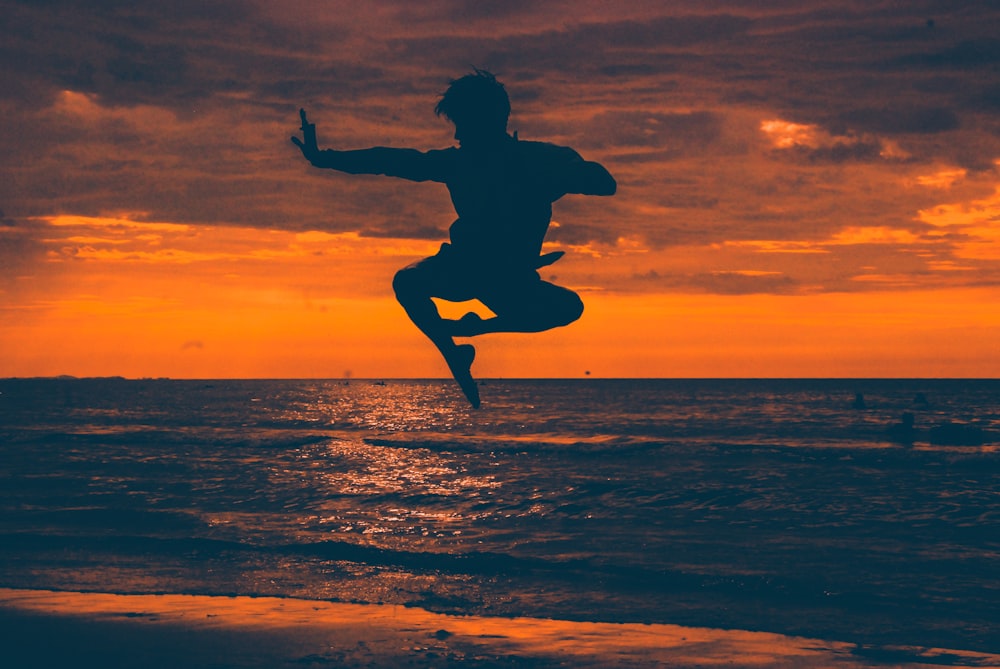 silhouette of man jump on seashore