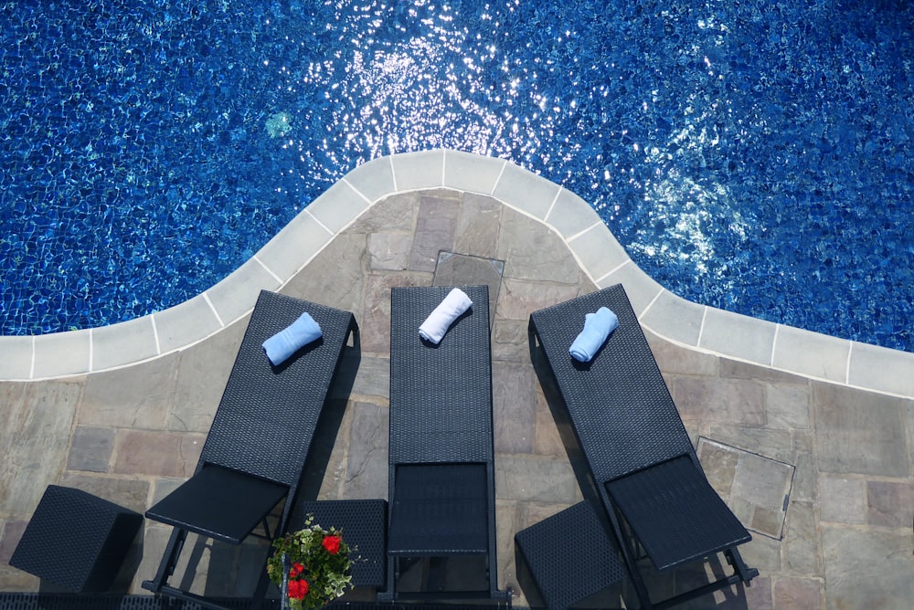 Trois chaises longues noires au bord de la piscine