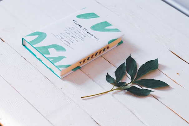 closed white book beside green leaf plant