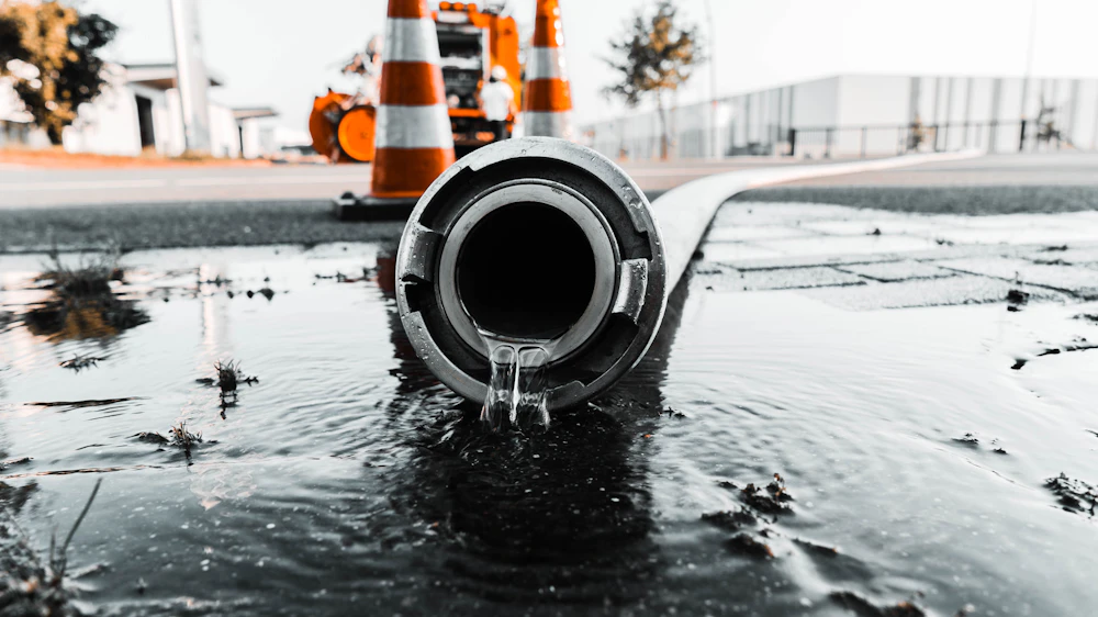 Water flowing from a pipe beside traffic cones
