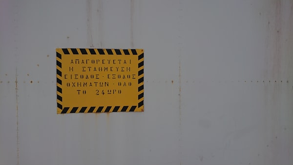 Placa de aviso amarela e preta em parede industrial