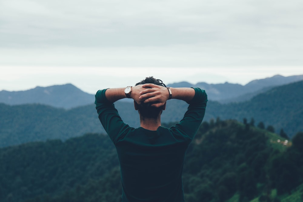 man wearing green raglan watching the mountain