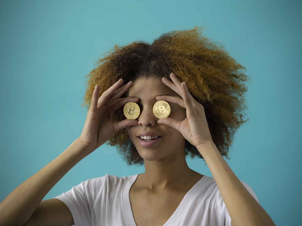 woman holding two round gold-colored coins