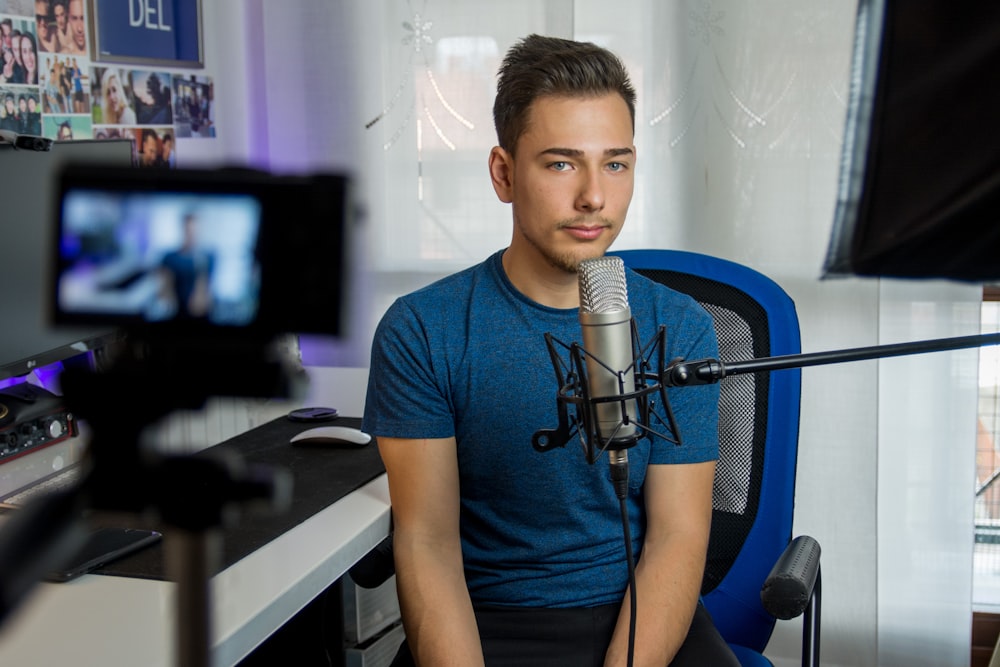 Homme assis sur une chaise devant un microphone à condensateur