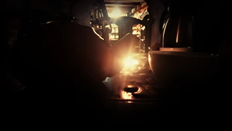 A dark romantic candlelit table setting featuring a ceramic mug with steam rising gently.