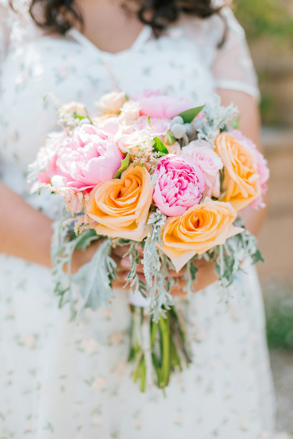 woman holding yellow, pin, and white flower bouquet