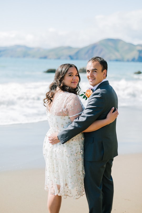 groom and bride standing on seashore in Baker Beach United States