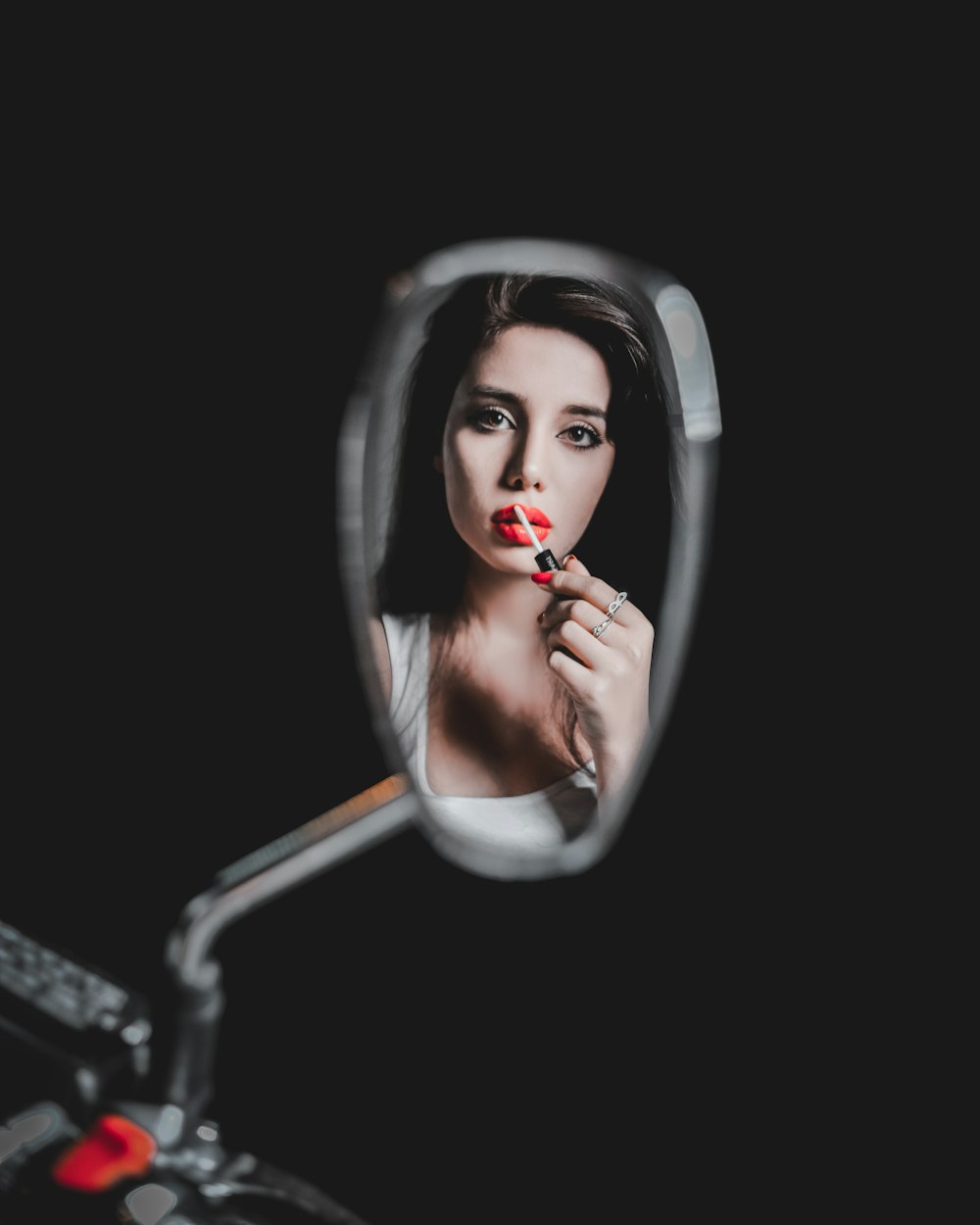 woman applying lipstick in front of wing mirror