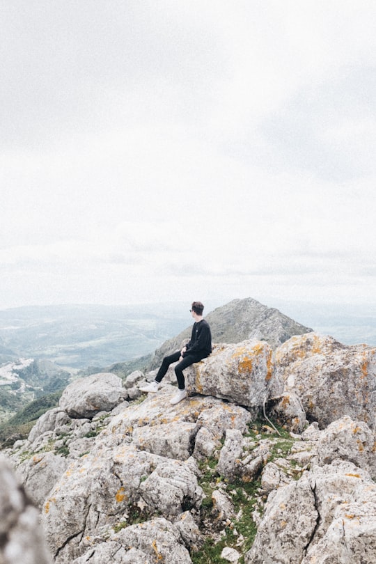 man sitting on rock at top of mountain in Casares Spain