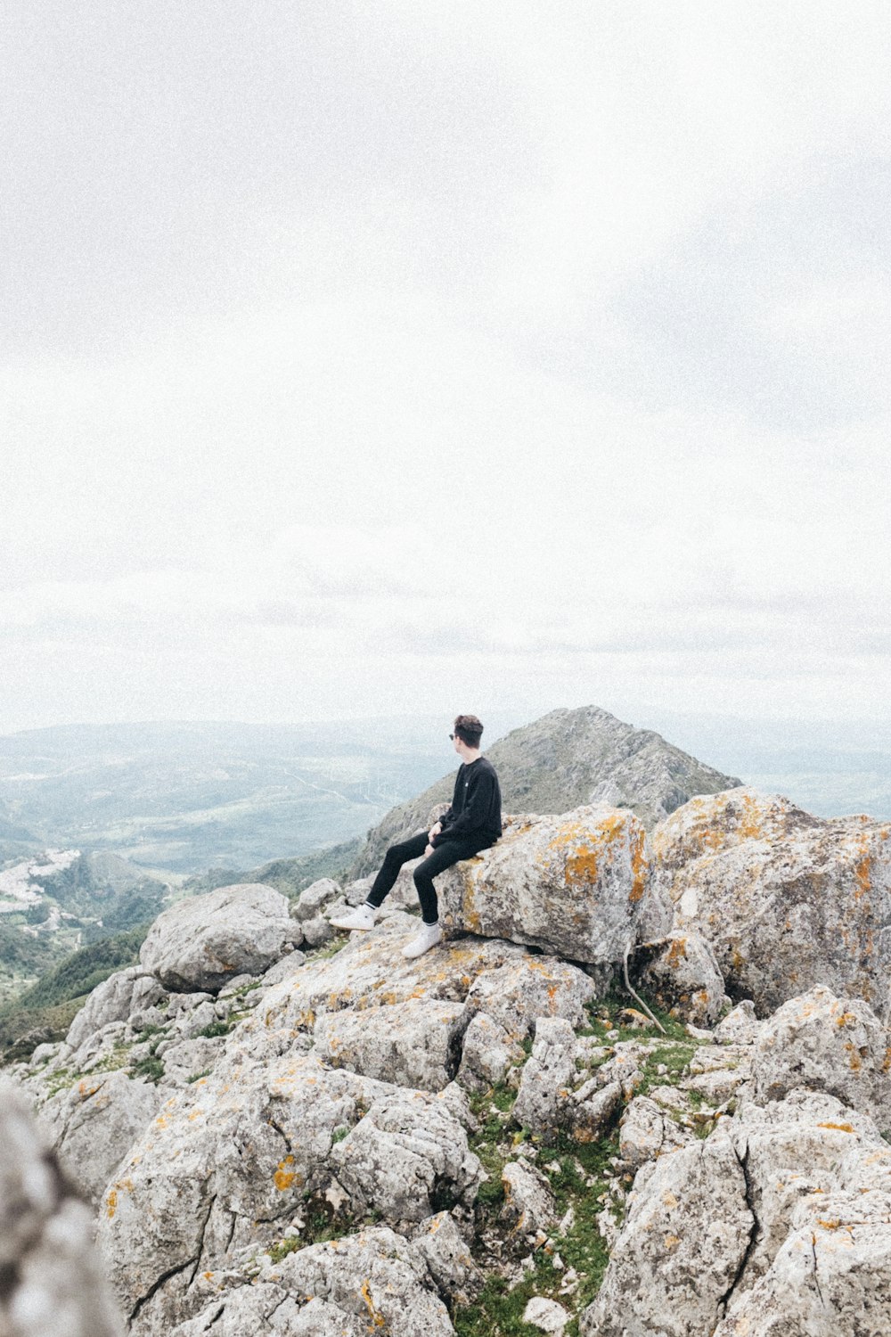 man sitting on rock at top of mountain