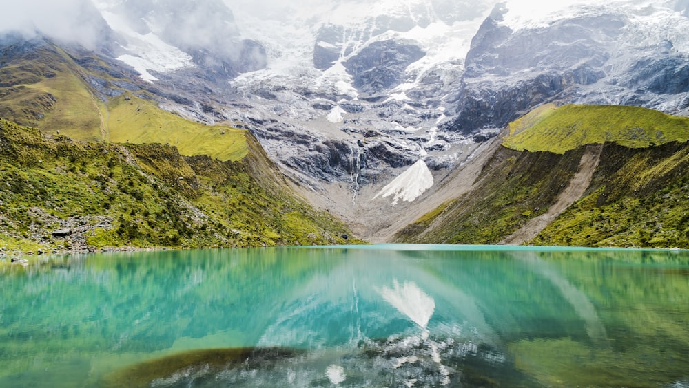 body of water with green mountains during daytime