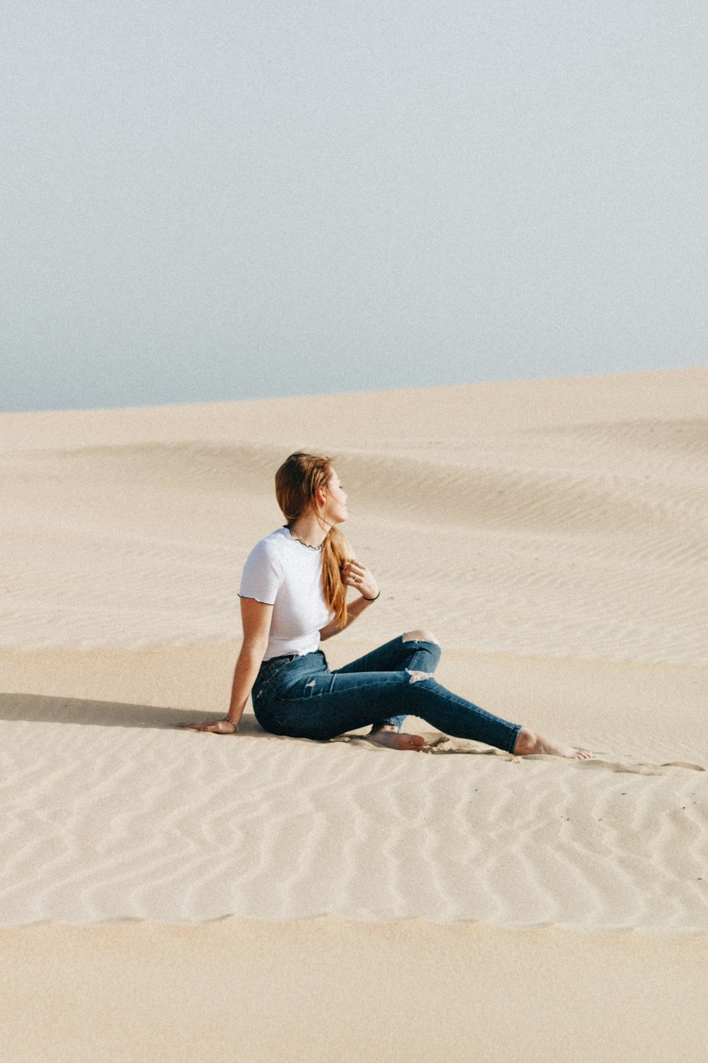昼間の砂漠に座る女性