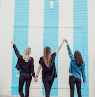 three woman holding hands white walking