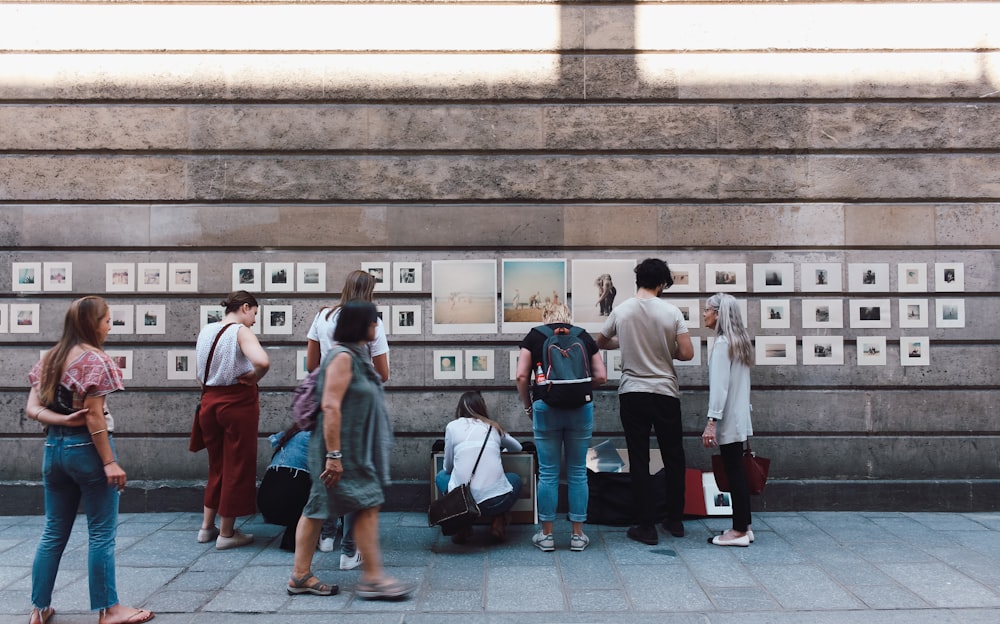 people beside brown wall