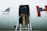 A person wearing a black jacket and beige pants is seen boarding an aircraft via a stairway attached to the plane. The aircraft is marked with the model number 'EMB 145' and features a white exterior with a partial red letter visible.
