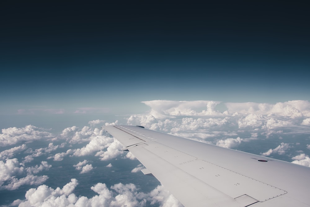 white plane wing above white clouds