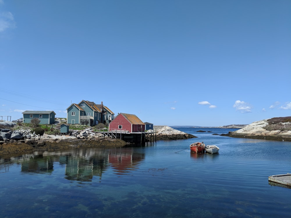 two assorted-color boats on body of water beside shore