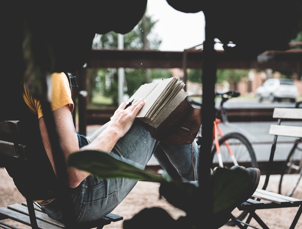 person sitting on wooden chair reading a book