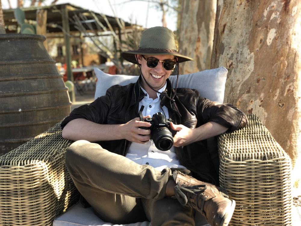 man sitting on chair while holding camera