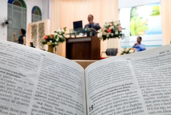 Apostle Kwame Adu speaking passionately at a community gathering surrounded by books.