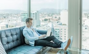 man sitting on sofa while using laptop