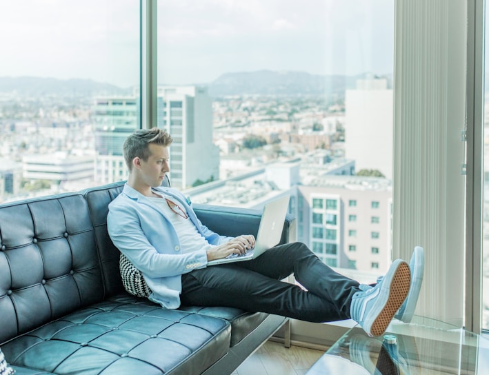 man sitting on sofa while using laptop