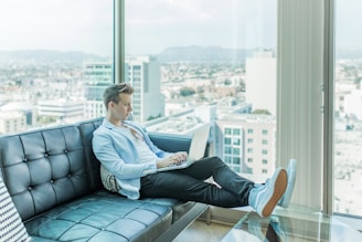 man sitting on sofa while using laptop