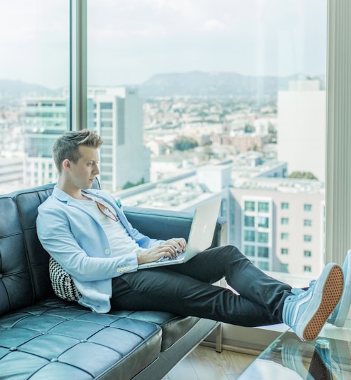 man sitting on sofa while using laptop