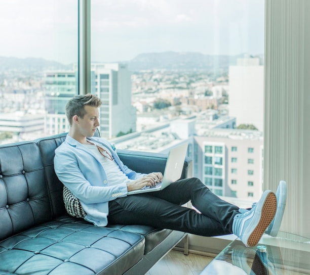 man sitting on sofa while using laptop