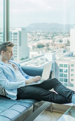 man sitting on sofa while using laptop