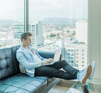 man sitting on sofa while using laptop