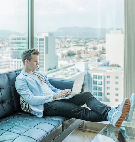 man sitting on sofa while using laptop