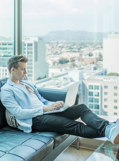 man sitting on sofa while using laptop