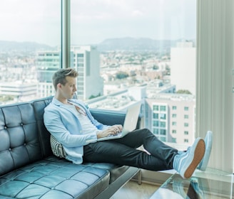 man sitting on sofa while using laptop