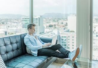 man sitting on sofa while using laptop