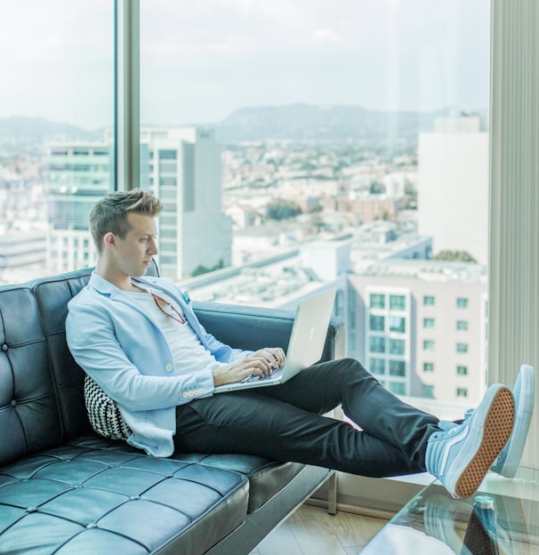 man sitting on sofa while using laptop