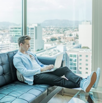 man sitting on sofa while using laptop