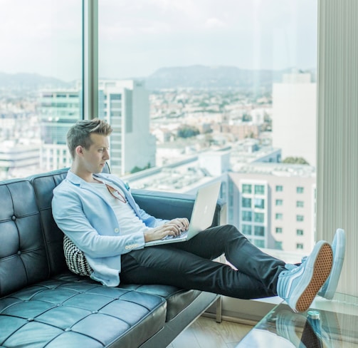 man sitting on sofa while using laptop