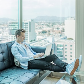 man sitting on sofa while using laptop