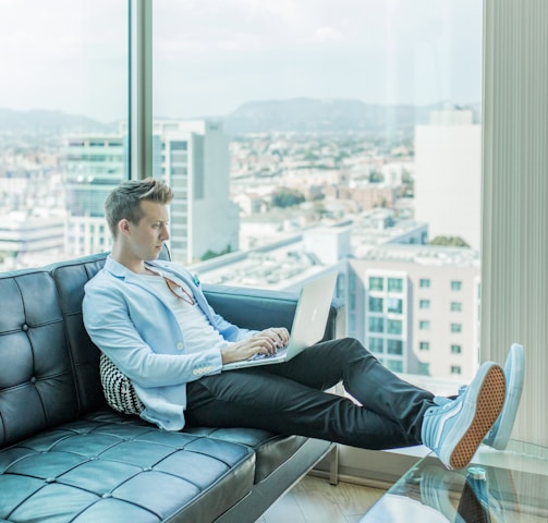 man sitting on sofa while using laptop