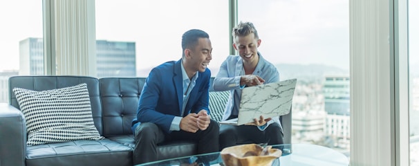 two men in suit sitting on sofa