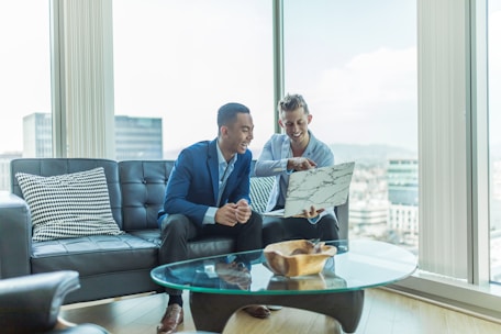 two men in suit sitting on sofa