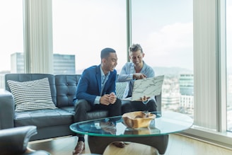 two men in suit sitting on sofa