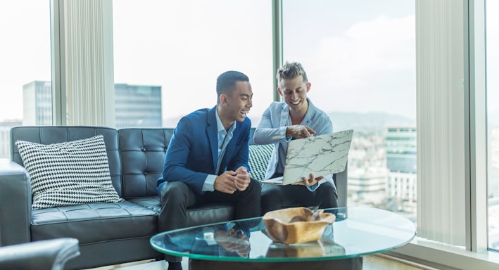 two men in suit sitting on sofa