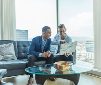 two men in suit sitting on sofa