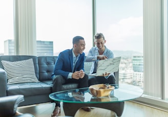 two men in suit sitting on sofa