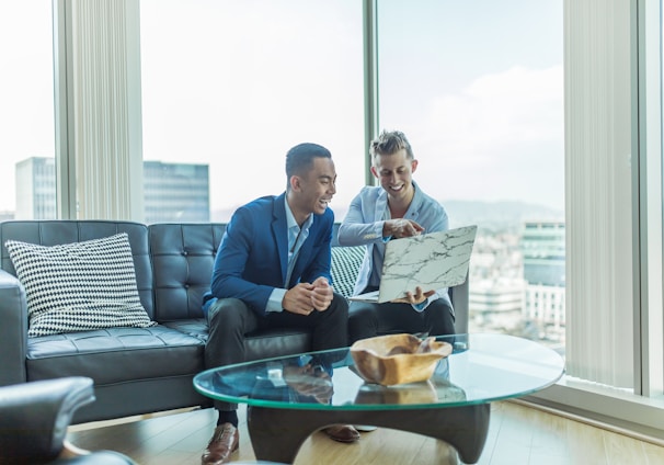 two men in suit sitting on sofa